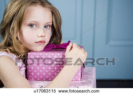 Young girl holding birthday presents looking unhappy View Large Photo Image Stock Photography - Young girl holding birthday presents looking unhappy. Fotosearch
