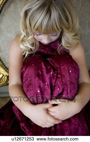Stock Image - Young girl in a party dress crying or sulking. Fotosearch
