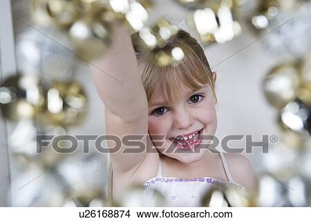 Picture - Young girl in a party dress, holding a Christmas decoration . Fotosearch