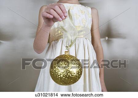 Young girl in a party dress, holding a Christmas decoration View Large Photo Image Picture - Young girl in a party dress, holding a Christmas decoration . Fotosearch