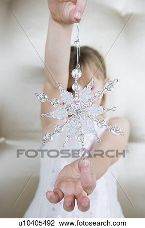 Young girl in a party dress, holding a Christmas decoration View Large Photo Image Stock Image - Young girl in a party dress, holding a Christmas decoration . Fotosearch