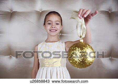 Young girl in a party dress, holding a Christmas decoration View Large Photo Image Stock Image - Young girl in a party dress, holding a Christmas decoration . Fotosearch