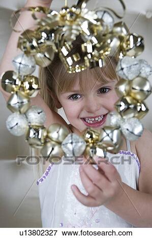 Stock Photo - Young girl in a party dress, holding a Christmas decoration . Fotosearch