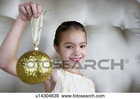 Young girl in a party dress, holding a Christmas decoration View Large Photo Image Stock Photo - Young girl in a party dress, holding a Christmas decoration . Fotosearch