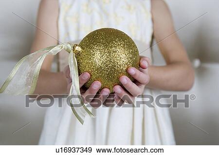 Young girl in a party dress, holding a Christmas decoration View Large Photo Image Stock Photo - Young girl in a party dress, holding a Christmas decoration . Fotosearch