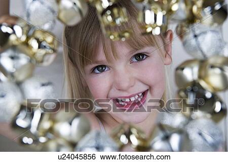 Young girl in a party dress, holding a Christmas decoration  View Large Photo Image Stock Photograph - Young girl in a party dress, holding a Christmas decoration . Fotosearch