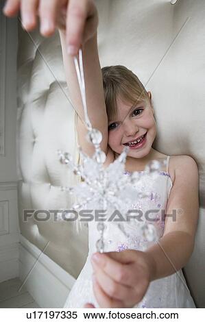 Young girl in a party dress, holding a Christmas decoration View Large Photo Image Stock Photography - Young girl in a party dress, holding a Christmas decoration . Fotosearch