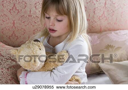 Stock Photography - Young girl in her bedroom hugging a teddy bear . Fotosearch