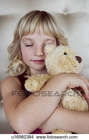 Picture - Young girl in party dress, holding a teddy bear. Fotosearch