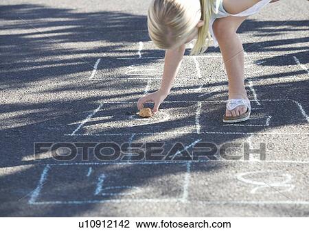 Stock Image - Young girl playing hopscotch. Fotosearch