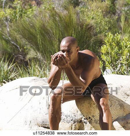 Young man drinking water from cupped hands View Large Photo Image Stock Photo - Young man drinking water from cupped hands. Fotosearch