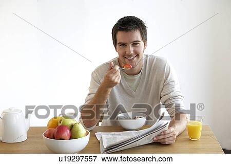Stock Photo - Young man having breakfast. Fotosearch