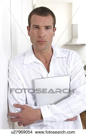 Young man holding a laptop View Large Photo Image Picture - Young man holding a laptop. Fotosearch