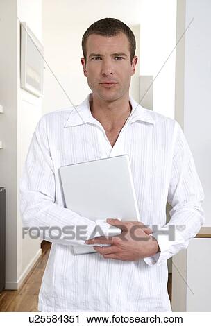 Stock Image - Young man holding a laptop. Fotosearch