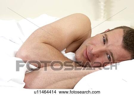 Young man laying in bed View Large Photo Image Picture - Young man laying in bed. Fotosearch