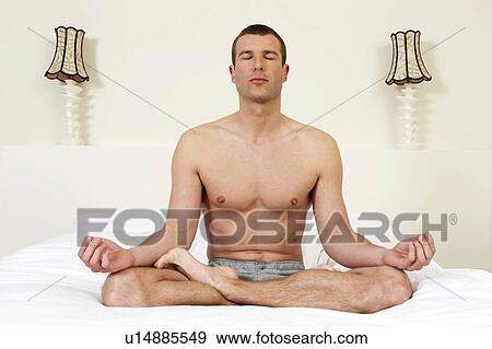 Stock Photo - Young man on bed practicing yoga. Fotosearch