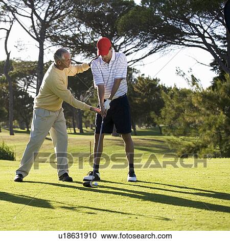 Stock Image - Young man receiving golf lessons. Fotosearch