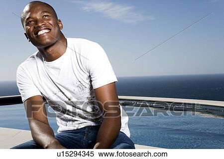 Young man sitting by the pool View Large Photo Image Stock Photography - Young man sitting by the pool. Fotosearch