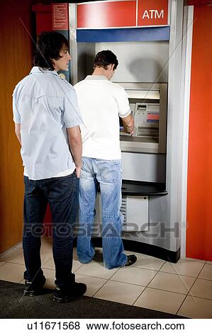 Stock Photo - Young man using a cashpoint or ATM. Fotosearch