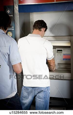 Stock Photography - Young man using a cashpoint or ATM. Fotosearch