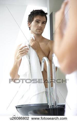 Stock Image - Young man washing in the bathroom. Fotosearch