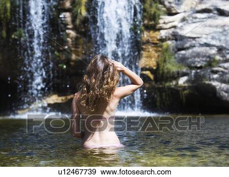 Stock Photo - Young woman in a bikini standing in a natural pool. Fotosearch