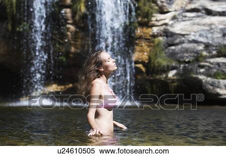 Stock Photography - Young woman in a bikini standing in a natural pool. Fotosearch