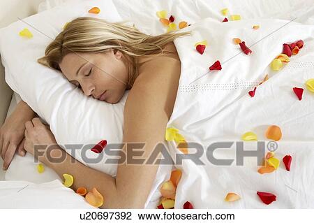 Stock Image - Young woman in bed, sleeping. Fotosearch