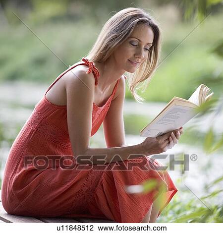 Stock Image - Young woman reading a book. Fotosearch
