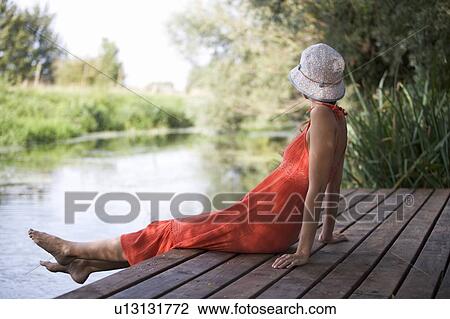 Young woman sitting by a river View Large Photo Image Stock Image - Young woman sitting by a river. Fotosearch