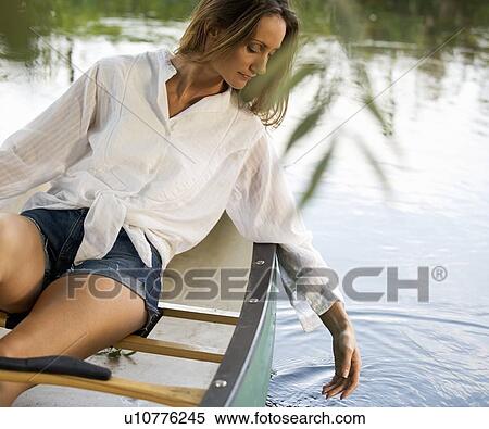 Stock Photography - Young woman sitting in a boat, trailing her hand in the water. Fotosearch
