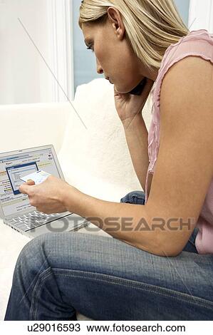 Young woman using a laptop and mobile phone at home View Large Photo Image Stock Image - Young woman using a laptop and mobile phone at home. Fotosearch
