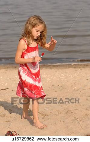 Stock Image - 5 year old on beach holding a lollypop. Fotosearch