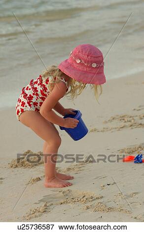 Stock Photo - A young girl (6-8) playing on a beach. Fotosearch