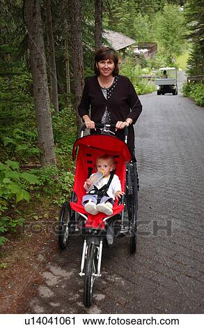 A young woman pushing a baby View Large Photo Image Stock Image - A young woman pushing a baby. Fotosearch