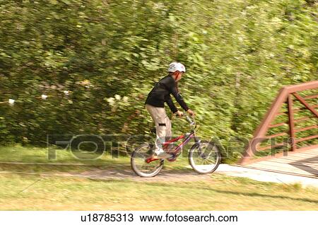 Stock Image - Child going over a bridge on a bike. Fotosearch