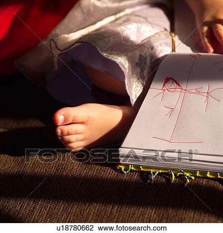 Stock Image - Child’s foot beside a sketch on paper. Fotosearch