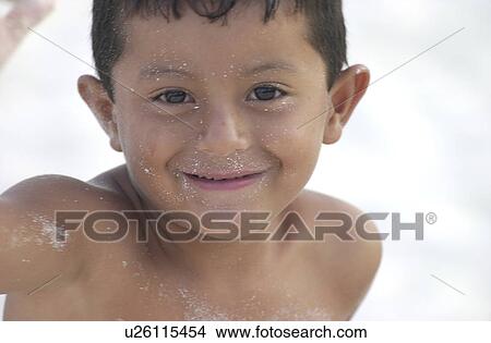 Close-up of a young boy playing with sand on the beach View Large Photo Image Picture - Close-up of a young boy playing with sand on the beach. Fotosearch