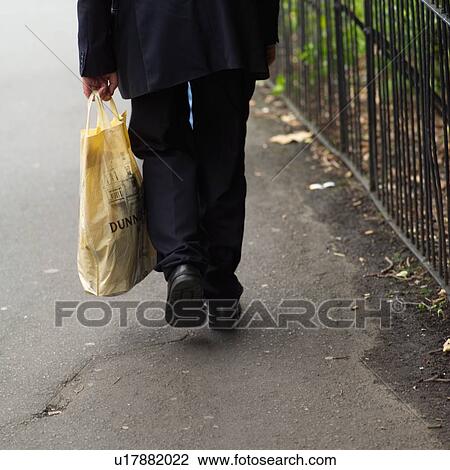 Stock Image - Dublin, Ireland – Person walking with shopping bag. Fotosearch