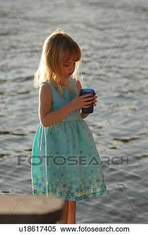 Stock Photography - Girl standing by the lake holding a glass. Fotosearch