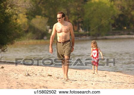 Stock Image - Matlock, Manitoba, Father and daughter walking along beach. Fotosearch