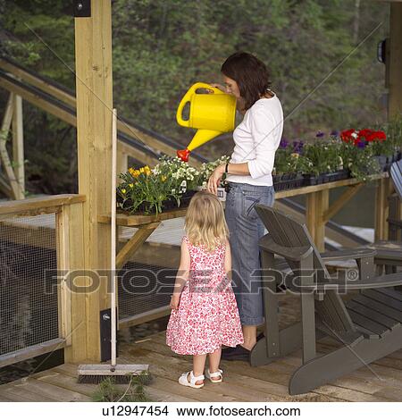 Picture - Mother Watering Plant with Daughter. Fotosearch