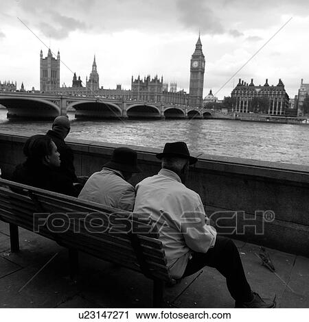 Stock Image - People sitting on a bench looking at Big Ben across the river Thames, London, England. Fotosearch