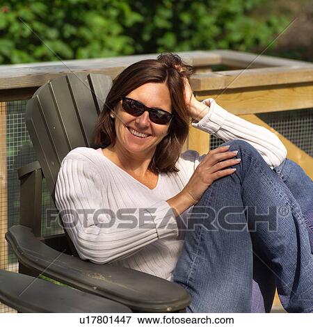 Portrait of a young woman sitting in a chair View Large Photo Image Stock Photo - Portrait of a young woman sitting in a chair. Fotosearch