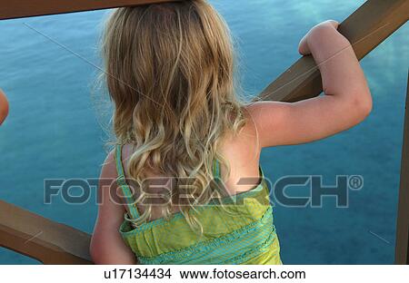 Rear of a young girl (6-8) looking at water View Large Photo Image Picture - Rear of a young girl (6-8) looking at water. Fotosearch
