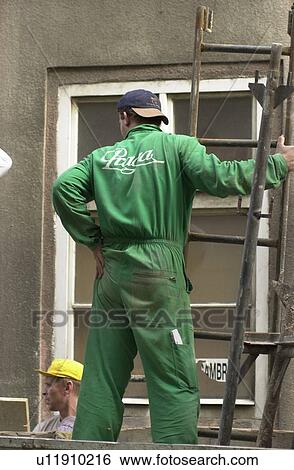 Stock Photograph - Rear view of a worker standing on a scaffolding in Prague. Fotosearch