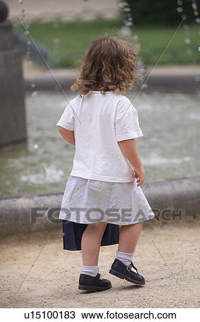 Stock Image - Rear view of a young girl walking. Fotosearch