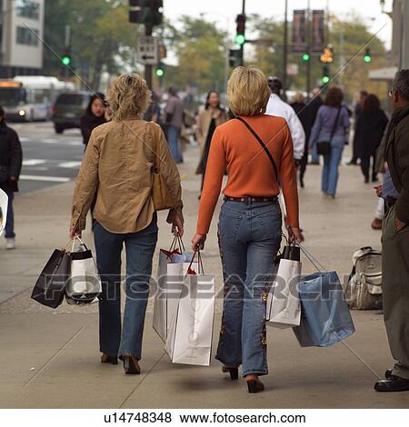 Rear view of people walking on a sidewalk View Large Photo Image Stock Photo - Rear view of people walking on a sidewalk. Fotosearch