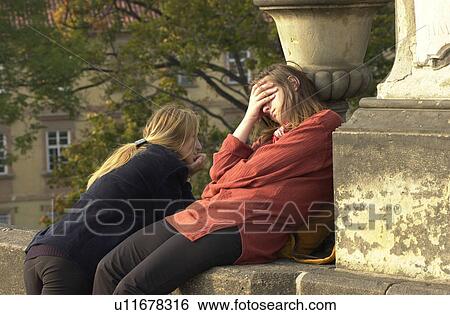 Stock Photograph - Two young women leaning on a wall in Prague. Fotosearch