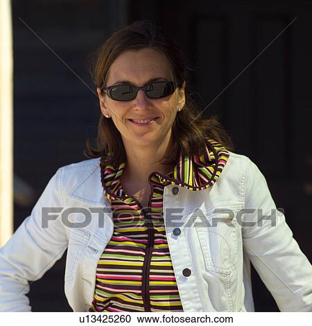 Stock Image - Woman wearing sunglasses looking at camera. Fotosearch